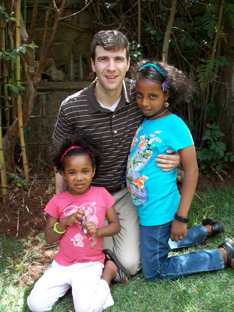 Man hugs two children